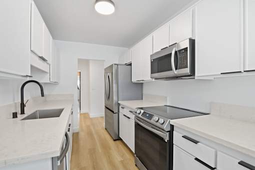 A kitchen with white cabinets and appliances.