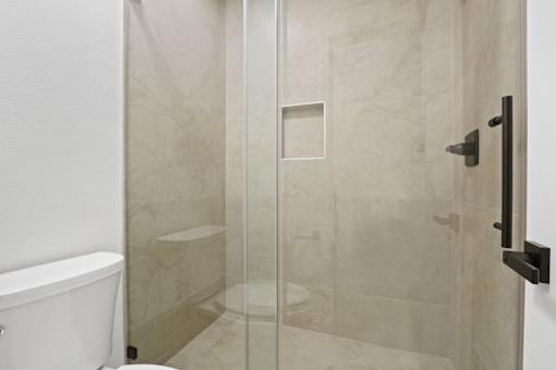 A white bathtub sits next to a glass shower door.