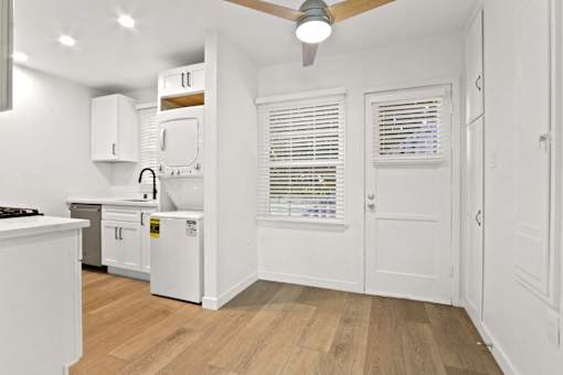 A kitchen with white cabinets and a wooden floor.