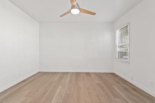 A room with a ceiling fan and wooden flooring.