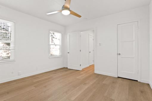 A room with a ceiling fan and three doors.
