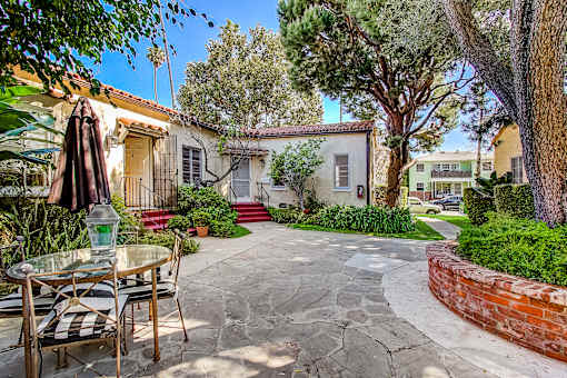 A patio with a table and chairs is surrounded by a brick wall and trees.