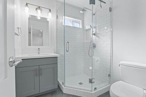 A white bathroom with a walk in shower and a toilet.