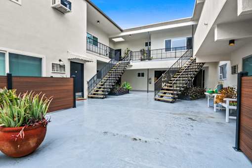 A large outdoor patio area with a staircase leading to a balcony.