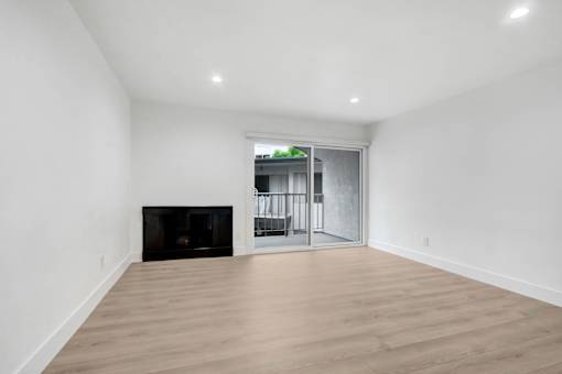 A room with a fireplace and sliding glass doors leading to a balcony.