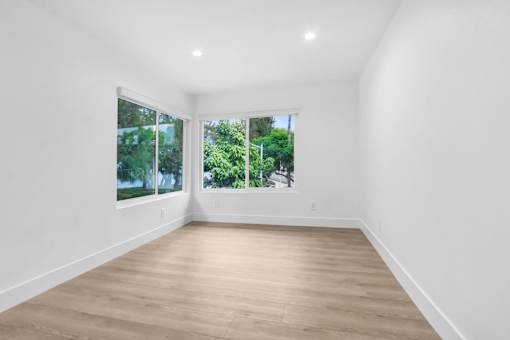 A room with wooden flooring and a window overlooking a green landscape.