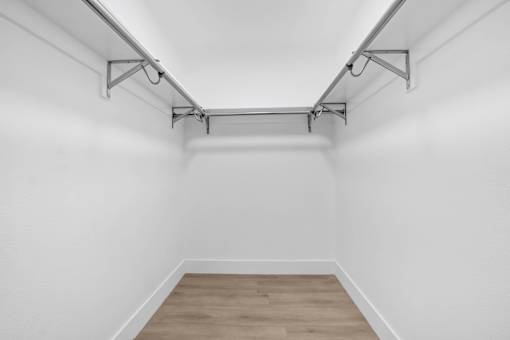 A white wall with a wooden floor and a metal rack on top.