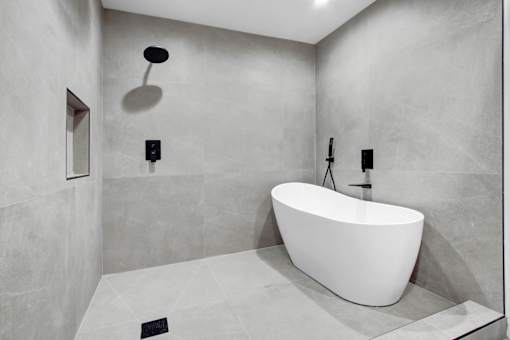 A white bathtub is in a bathroom with grey walls.