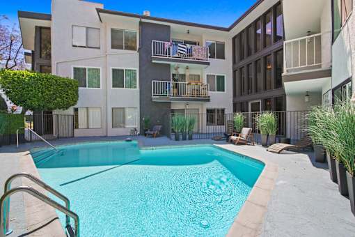 A swimming pool in front of a modern apartment building.