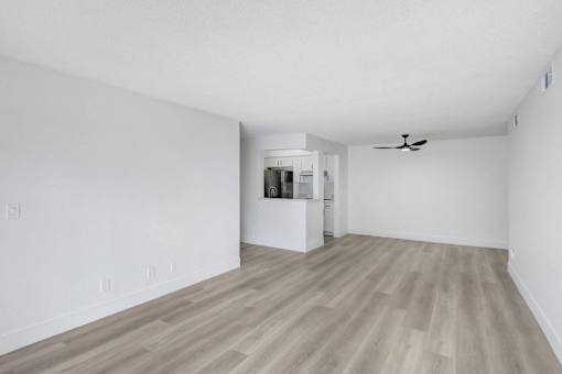 A room with a ceiling fan and a small kitchenette.