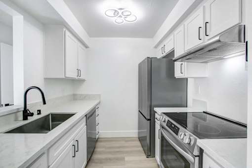 A modern kitchen with a refrigerator, stove, and sink.