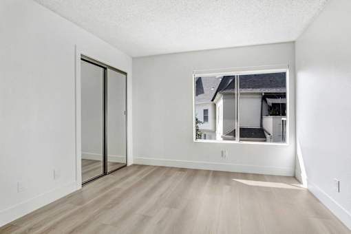 A room with a sliding glass door and wooden flooring.