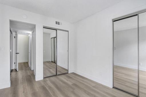 A hallway with a mirrored door and a wooden floor.
