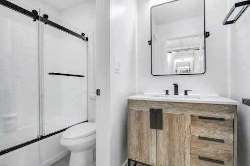 A bathroom with a white toilet and a wooden cabinet.