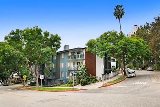 A street view of a residential area with a blue building on the left and a white building on the right.