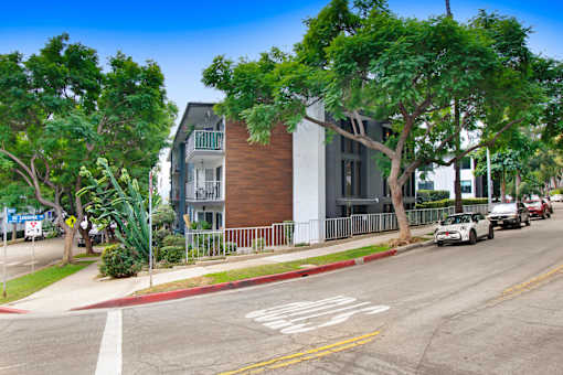 A street view with a car driving on the road and a building on the side.