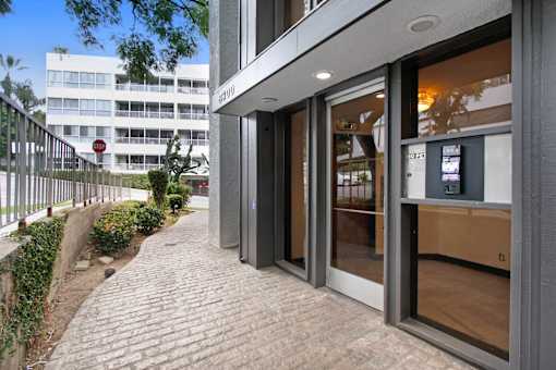 A building with a glass door entrance and a brick pathway leading to it.