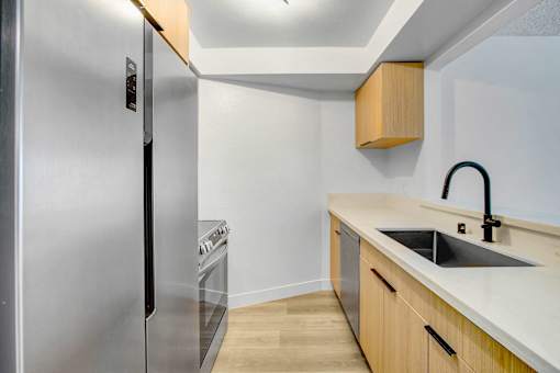 A modern kitchen with a stainless steel refrigerator and wooden cabinets.