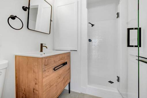 A bathroom with a wooden vanity and a white toilet.