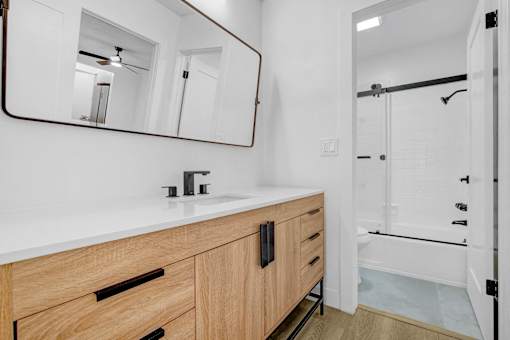A bathroom with a sink, mirror, and a shower.