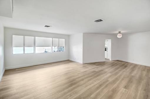 A room with wooden flooring and a large window.
