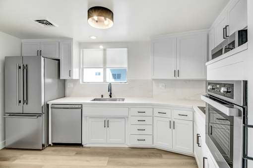 A modern kitchen with white cabinets and stainless steel appliances.