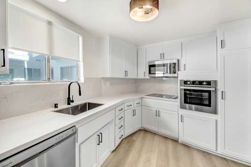 A white kitchen with a stainless steel dishwasher and oven.