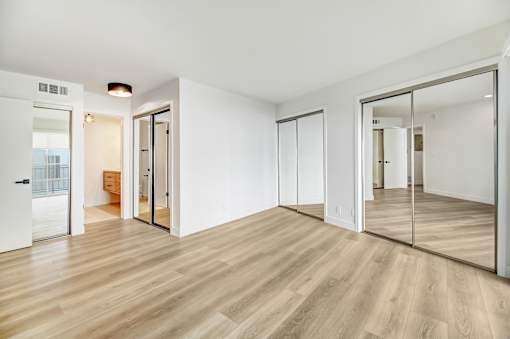 A room with wooden floors and white walls with a large mirror on the wall.