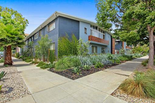 A modern apartment building with a well-maintained garden in front.