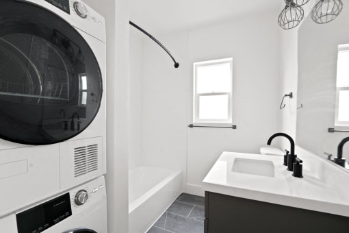 a washer and dryer in a bathroom with a sink and a tub