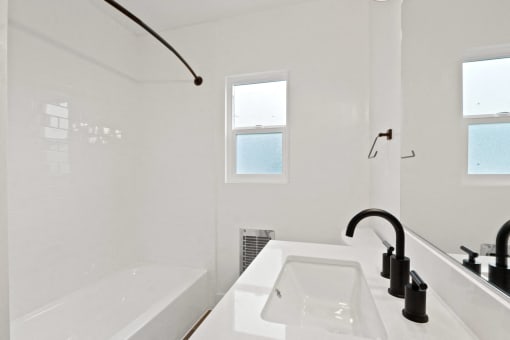 a white bathroom with a sink and a bath tub