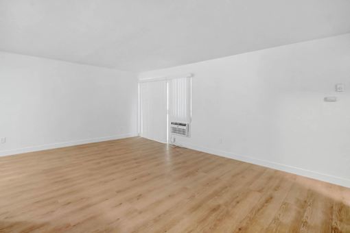 an empty living room with white walls and wood floors