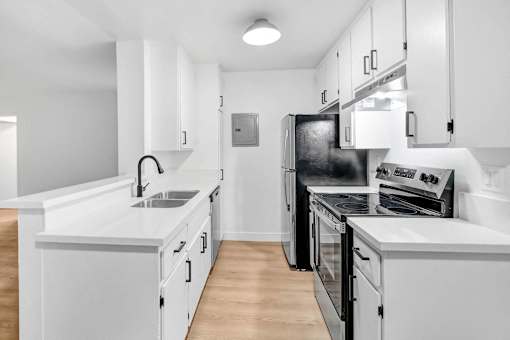 a white kitchen with white cabinets and black appliances