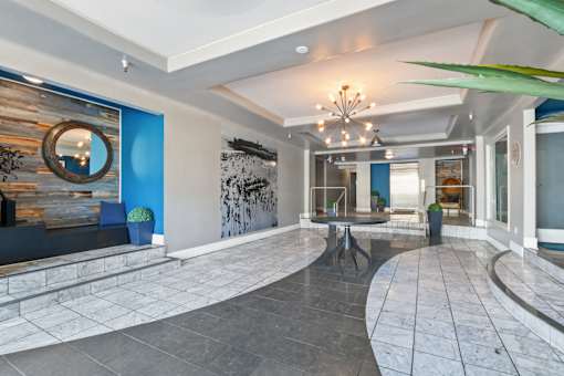 A large, open living space with a stone floor and a chandelier hanging from the ceiling.