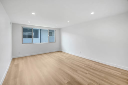 A room with a window and wooden flooring.