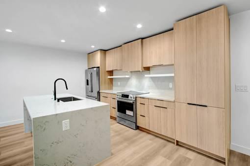 A modern kitchen with wooden cabinets and a marble island.