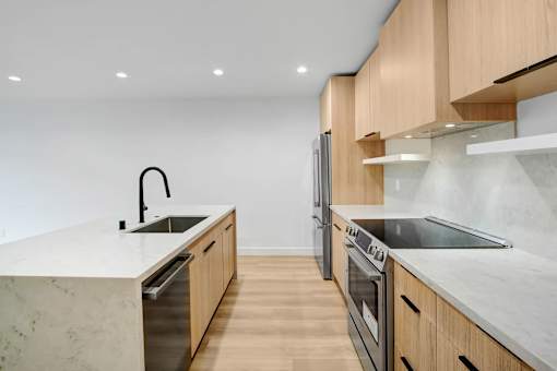 A modern kitchen with wooden cabinets and marble countertops.