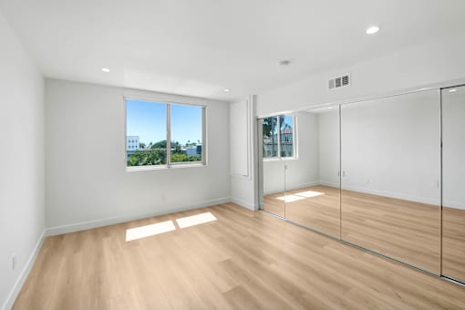 A room with a large window and a wooden floor.