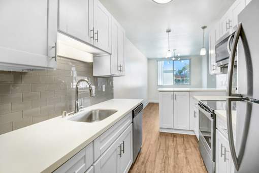 A kitchen with white cabinets and a stainless steel refrigerator.