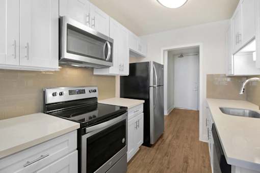 A kitchen with white cabinets and black appliances.