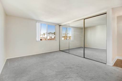 A room with a glass door and a window overlooking a balcony.