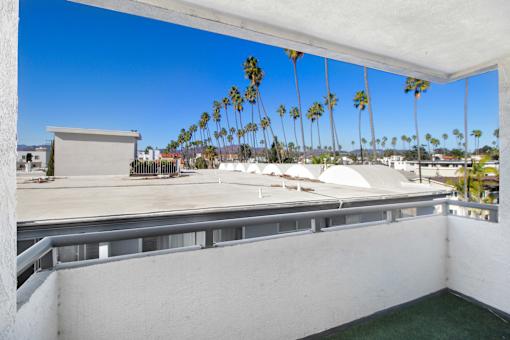 A balcony with a view of palm trees and a building.