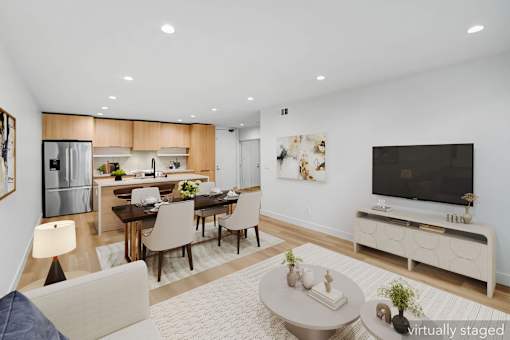A modern living room with a dining area and a kitchen in the background.