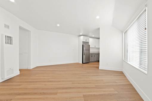 A kitchen with white cabinets and a wooden floor.