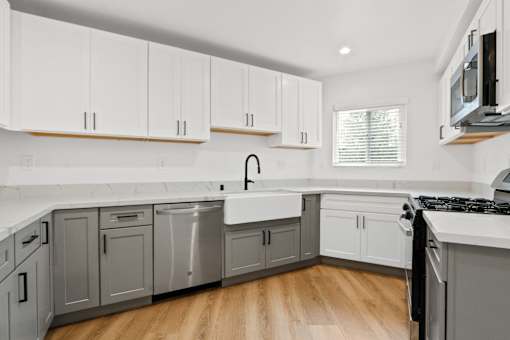A kitchen with white cabinets and a wooden floor.