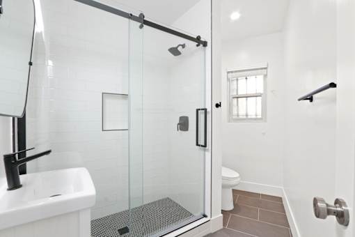 A white sink is on the left of a glass shower stall.