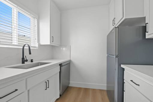 A kitchen with white cabinets and a grey refrigerator.