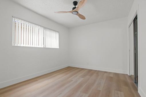 A room with a ceiling fan and a window with blinds.