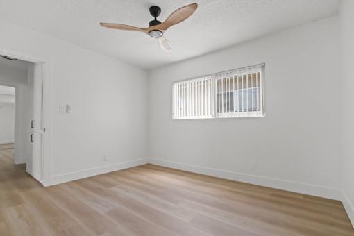 A room with a ceiling fan and a window with blinds.