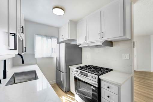 A modern kitchen with white cabinets and appliances.